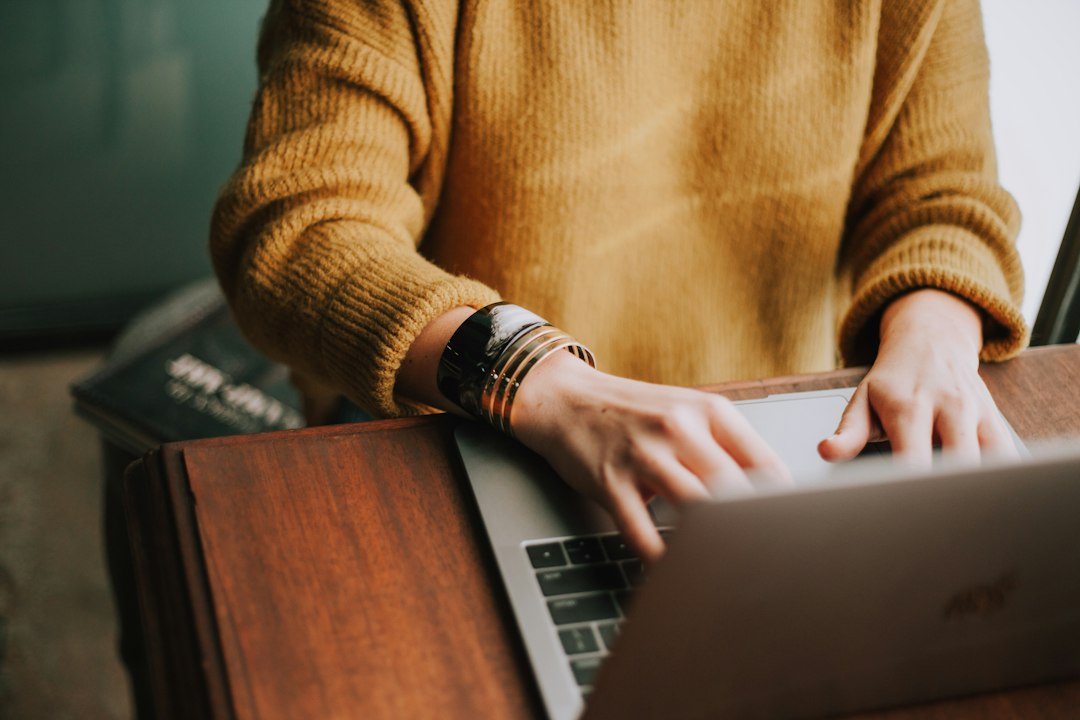 Close-up of a person typing on a laptop with a modern travel contract document next to it, symbolizing strict cancellation policy clauses.