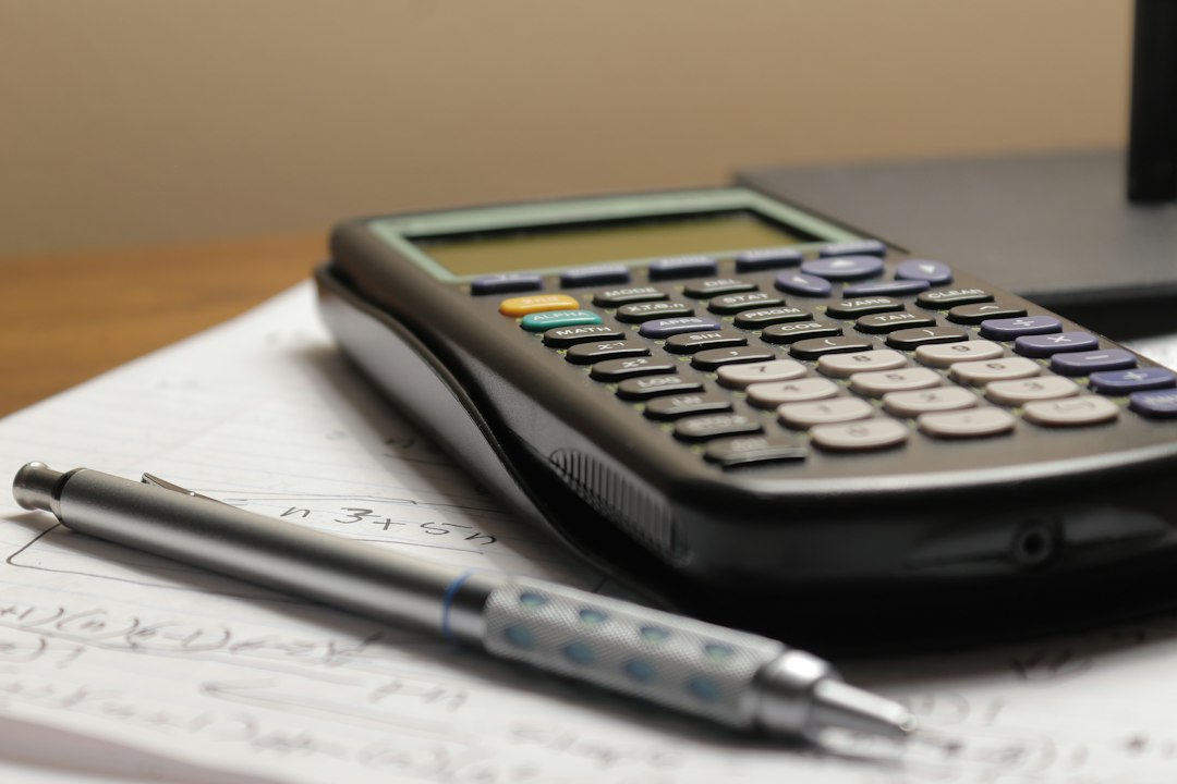 Extended Stay Hotel vs. Monthly Airbnb: Which Costs Less 5 Close up of a calculator on a wooden desk showing travel budgeting spreadsheets on a laptop.